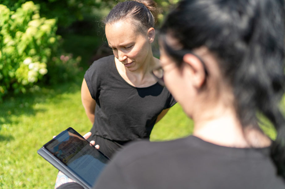 Eine Immobilienmaklerin zeigt einer Kundin das Exposé am Tablet