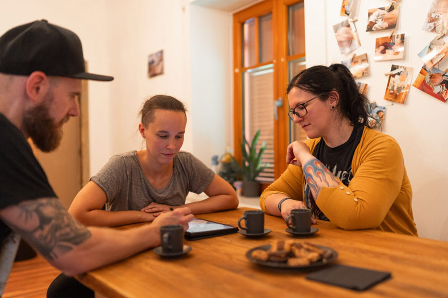 Zwei Makler beraten eine Interessentin bei einer Tasse Kaffee