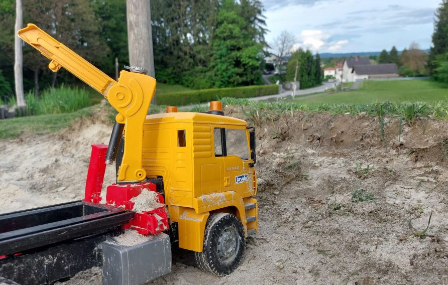 Ein Spielzeug Baufahrzeug im Sand (steht für das Baurecht im Immobilienbereich)