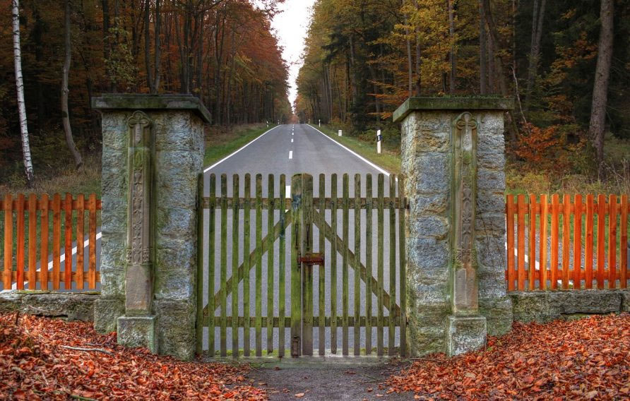 Ein Tor in einer Zufahrt zu einem Grundstück und eine Straße.